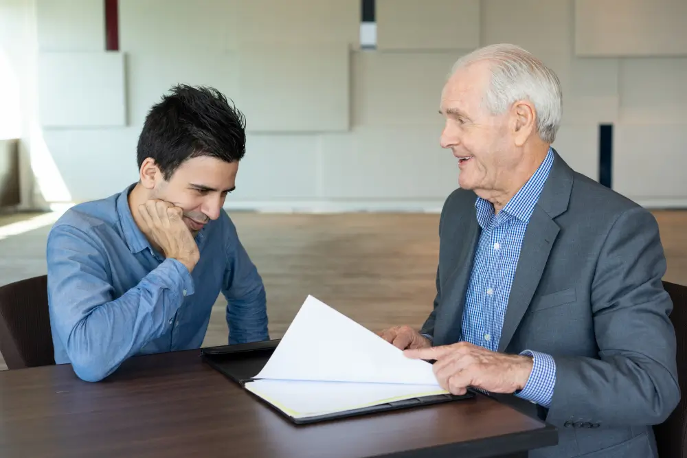 Protecting Inheritance from a Greedy Stepson - Elderly man signing estate documents with a suspicious stepson watching in the background